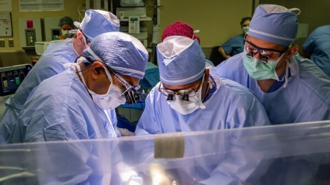 Surgeons hover over a patient in an operating room.