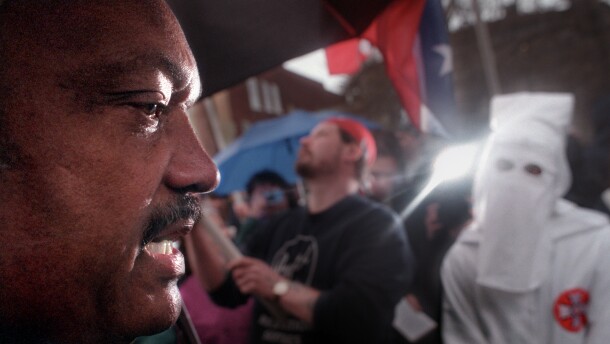 FILE 04/26/00: Before going inside St. Paul's Episcopal Church to attend a prayer service in honor of Martin Luther King, Jesse Jackson (L) meets with group of people protesting Wallingford's observence of Martin Luther King Day as a town holiday. A representative of the national Knights of the Ku Klux klan was one of about 50-people protesting the holiday. Jackson led a candle light vigil walk of about 250 people down Wallingford's Center Street to town hall where Jackson addressed the crowd.