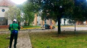A Colombian police officer inspects some of the burning wreckage after a guerrilla car bombing at a Bogota police academy on Jan. 17.