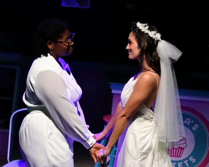 An African American bride and Caucasian bride hold hands. 