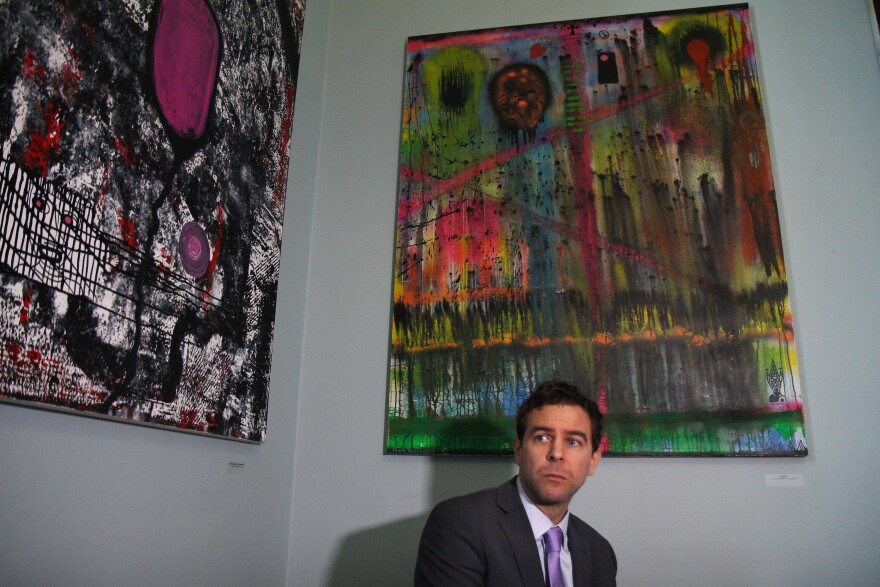 Senate President Pro Tem Tim Ashe sits below two paintings hanging on a wall