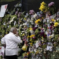 A man looks at a memorial Tuesday with pictures of some of the missing from the partially collapsed 12-story Champlain Towers South condo building in Surfside, Fla.