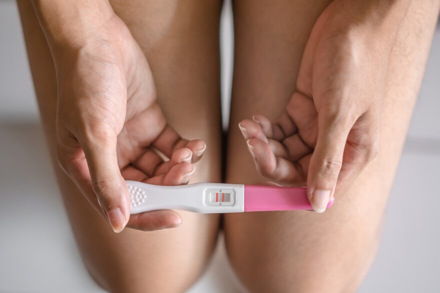 Young woman holding pregnancy test showing a positive result in bedroom, Wellness and healthy concept, Abortion problem, Selective focus.