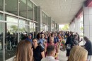 A gorup of people line up outside a car dealership waiting for their audition to be on "The Price is Right"