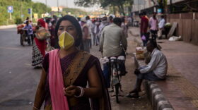 A woman covers her face with a mask as she walks in a crowded New Delhi market place, during India's nationwide lockdown.
