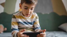 one boy caucasian child preschooler hold smartphone mobile phone at home play video games childhood and growing up technology addiction concept use smartphone app for online browsing or watch video