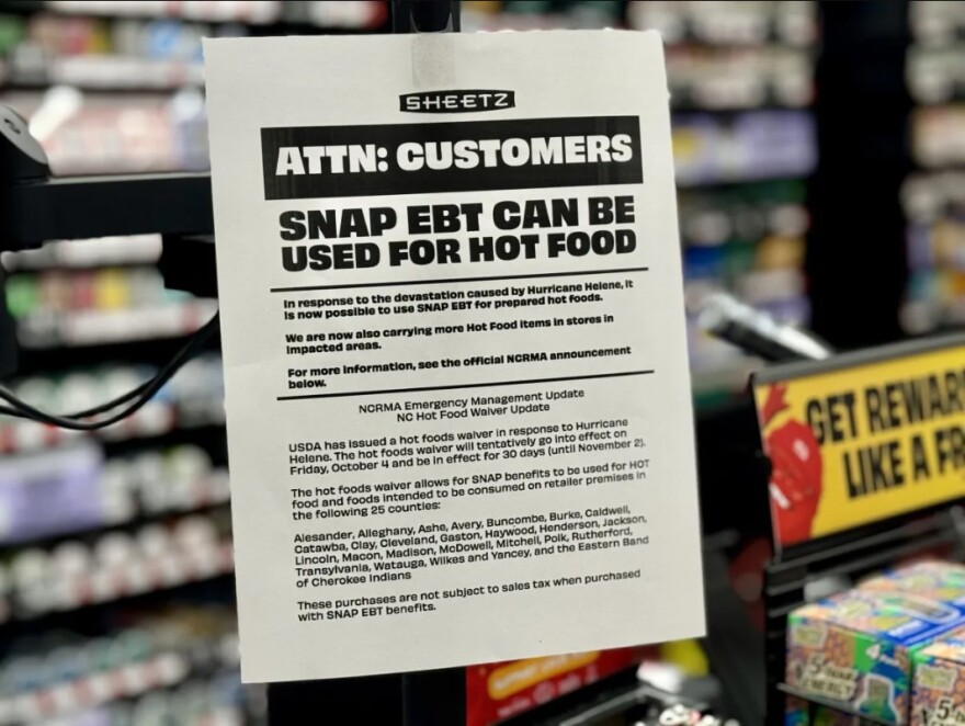 Sign at a convenience store informing SNAP participants that hot food is temporarily covered by the program.