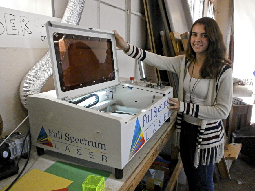 Jessie Davidson shows the school's laser cutter, which is used to burn the school insignia onto plastic objects, among other things.