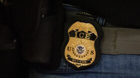A U.S. Immigration and Customs Enforcement badge on a belt