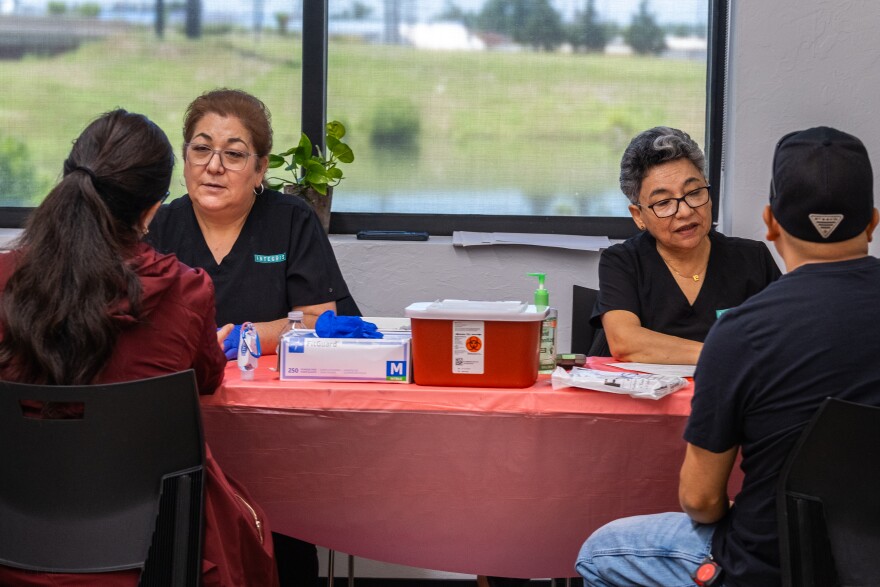 Assistant Leticia Orozco, left, and Dr. Carmen Romo, right, talk to clients while testing them for signs of diabetes during a health fair on June 6, 2025, at the Mexican Consulate in Oklahoma City.