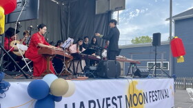 Performers in traditional Chinese dress and playing various traditional instruments sit on stage during the 2024 Harvest Moon Festival at Schoen Place in Pittsford.