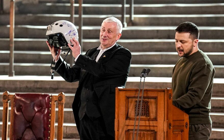 Speaker of the House of Commons Lindsay Hoyle (left) holds the helmet of a Ukrainian pilot, inscribed with the words "We have freedom, give us wings to protect it." It was presented to him by Ukraine's President Volodymyr Zelenskyy (right) during his address to British members of Parliament Wednesday.