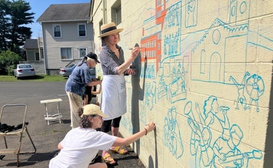 Rochelle Shicoff, Nancy Meagher and Deborah Sacon work on a new mural about local history in Florence, Massachusetts. Shicoff is the lead artist on the mural. Meagher and Sacon are part of the team that researched and designed it.