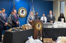 Law enforcement officials standing at table with drugs and guns