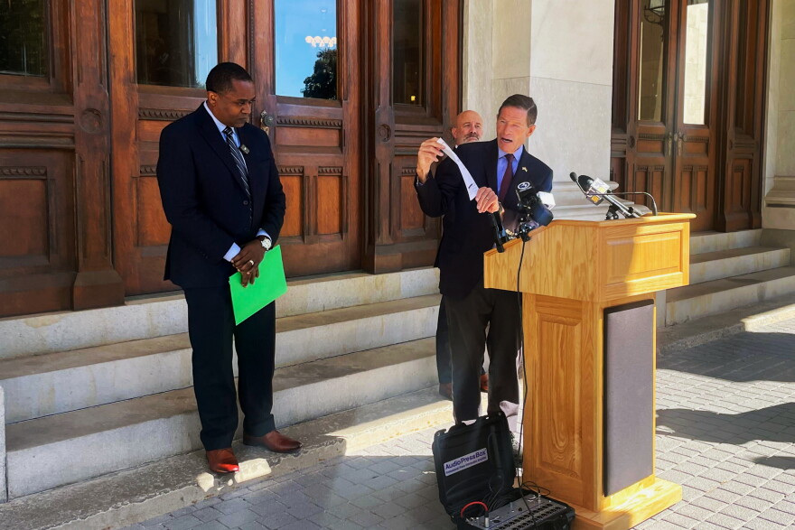 Sen. Richard Blumenthal at then podium with Perkin Simpson from Generation Power CT on the left and Christopher McCluskey from Community Renewal Team on the far right outside the State Capitol 0n October 6th 2026 talking about rising oil prices.