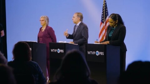 Three candidates stand at podiums during a debate