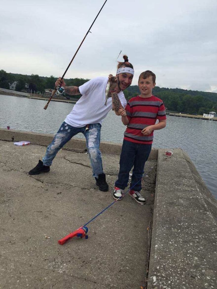 Two people on a dock with fishing poles, leaning in for a photo.