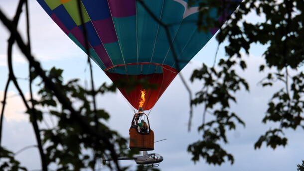 A balloon called the Fleckfolly 5 soared overhead while passengers in a helicopter ride look on at the Suncook Valley Rotary's 44th annual hot air balloon rally on Friday July 31, 2026.