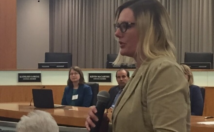 Woman with microphone in council chambers.