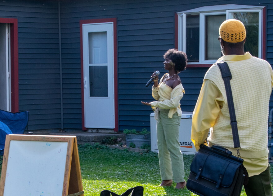 A teenager delivers spoken-word poetry while her father looks on, recording.