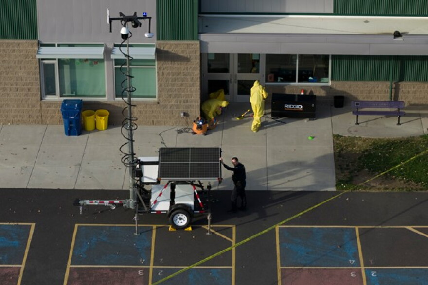 Hazardous materials workers clean up broken glass on the scene at Silver Rail Elementary School.
