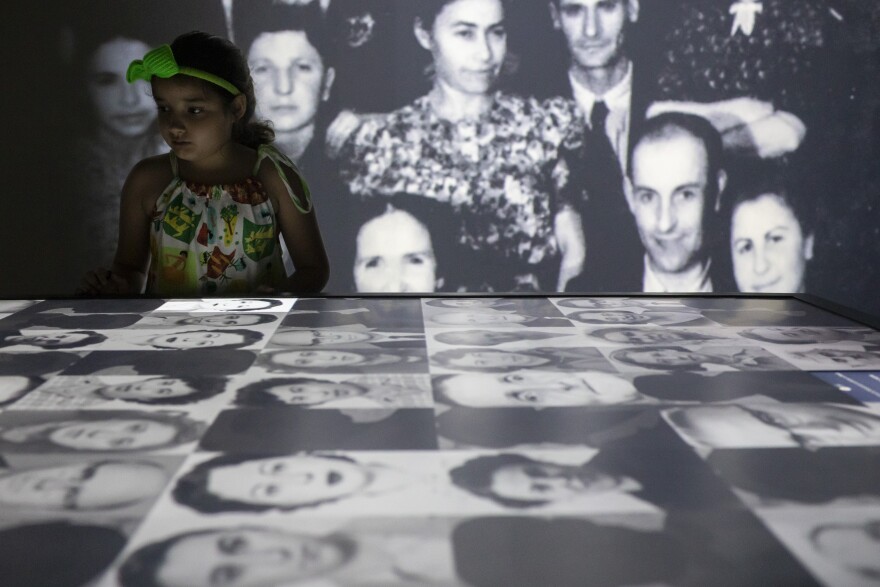 A youth looks at photos on an interactive table displaying the photos and stories of the thousands of people who took refuge in Brazil during the Holocaust at the Holocaust Victims Memorial. (AP Photo/Bruna Prado)