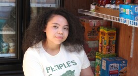 Ziona Brownlow sits in the Mountain View community fridge. (Wesley Early/Alaska Public Media)