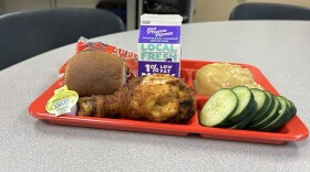 A tray with meat, veggies, potatoes and a small carton of milk. 