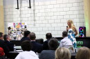 A woman stands in front of a crowd giving a speech