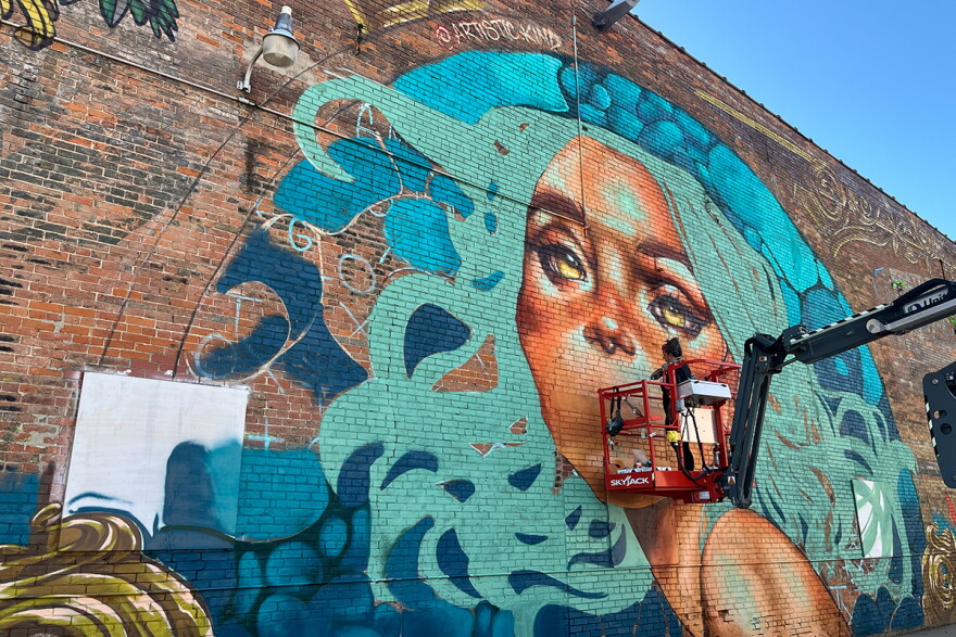 An artists paints a mural in downtown Clinton during the 2026 Paint it Back festival.