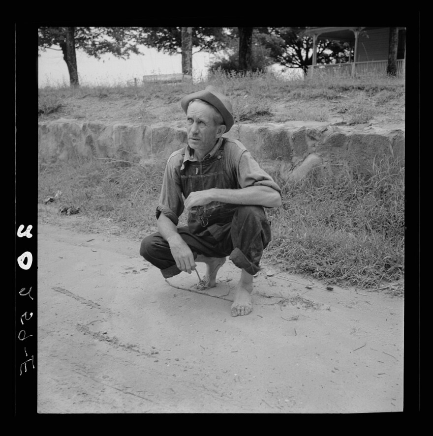 Roadside meeting with Durham County farmer. North Carolina. He gives road directions by drawing the dirt with a stick. July 1939