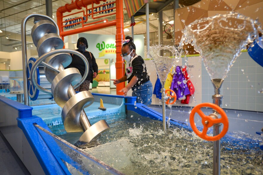 Sherita Neal watches her daughter, Layla, 5, usher a toy boat through the Water Works play area inside Wonderscope on Tuesday.