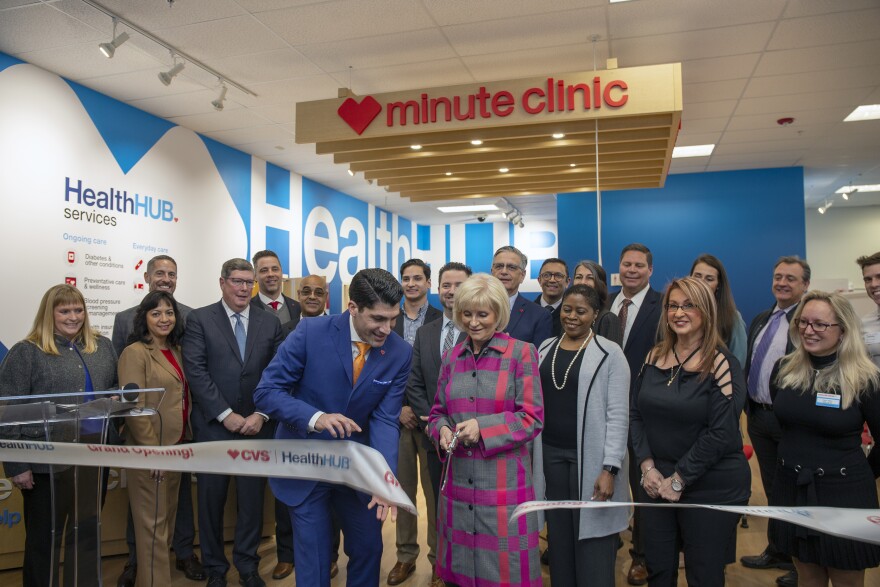 A group of people cut a CVS ribbon to symbolize the opening of the new clinic.