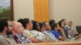 A group of people sit in the front row of the Normal Town Council meeting. 