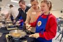A volunteer helps Carley Zagalik prepare french toast.
