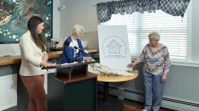 Meghan Loftus, left, president/CEO of Friends of the Poor & Catherine McAuley Center, stands by as the organizations new logo is unveiled.