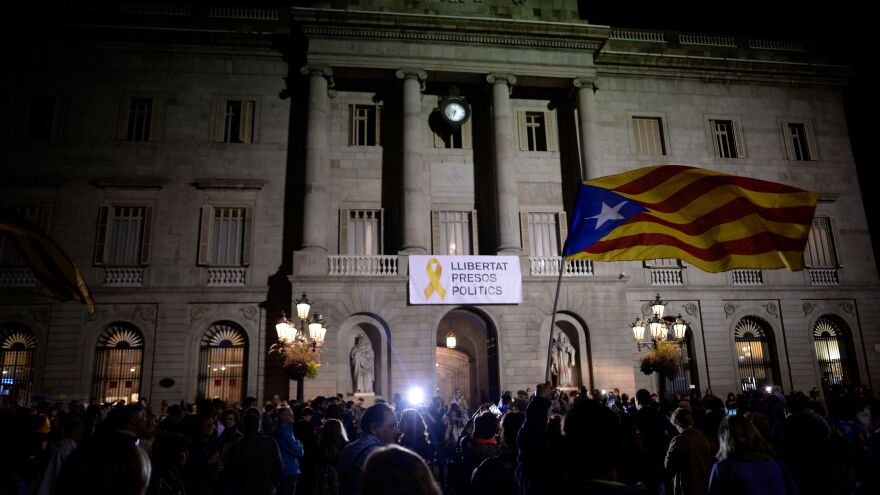 A banner reading "Freedom to political prisoners" hangs from City Hall in Barcelona as a protester waves a Catalan pro-independence Estelada flag during a demonstration on Friday to protest the detention of Catalan officials.