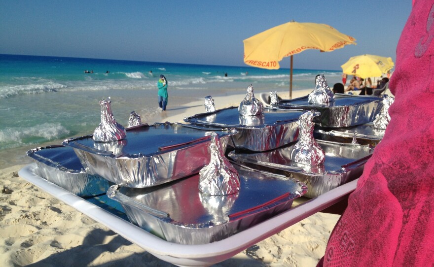 Vendor Amr Abd Elaal balances a tray of gandoufly steamed clams and foil-wrapped half lemons.