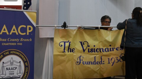 Members of the Alachua County NAACP and Visionaires Inc. help set up before the meeting begins. (Harrison Leveton/WUFT News)