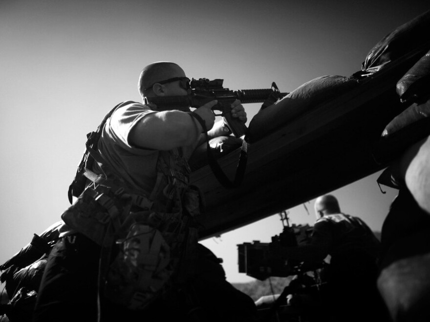 PFC Thomas Packer from Tama, Iowa, looks through the scope on his rifle as incoming mortar rounds hit just outside the bunker at Combat Outpost Wilderness in Paktia province.