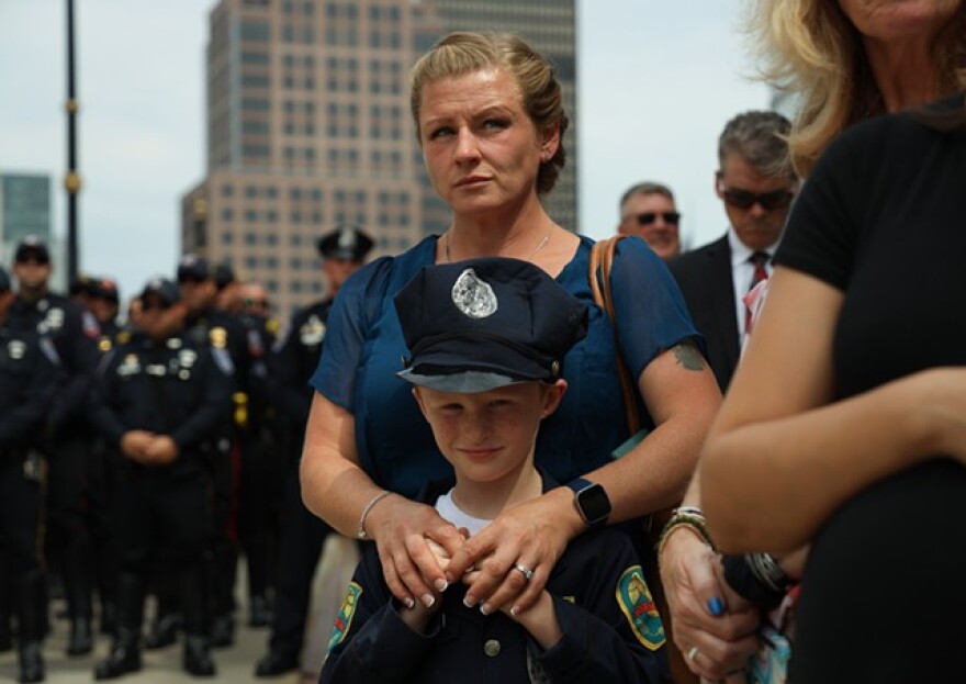 Megan Millspaugh and her son, Macsen, watch the presentation of the flag to Rochester Police Officer Anthony Mazurkiewicz's family after his funeral. Millspaugh's husband is a Rochester police officer.