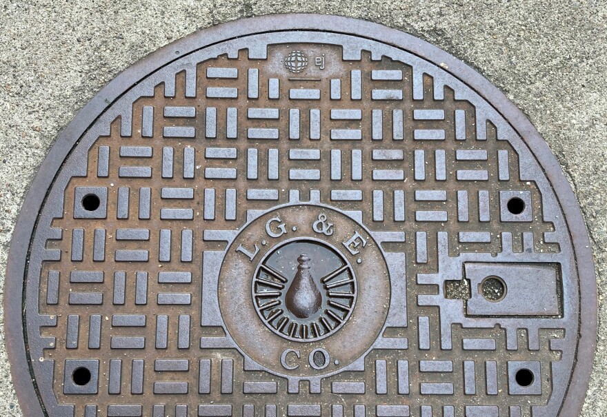 LG&E Co. branding sits on the top of a manhole cover on the street.