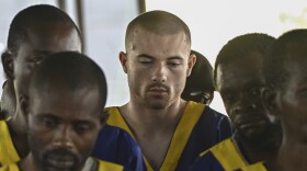 American Tyler Thompson Jr, center, sits in court in Kinshasa, Friday, June 7, 2024. Three Americans accused of a role in May's attempted coup in Congo appeared in court in Kinshasa on Friday, among a total of 53 defendants who were lined up on plastic chairs before the judge on the first day of the hearing.