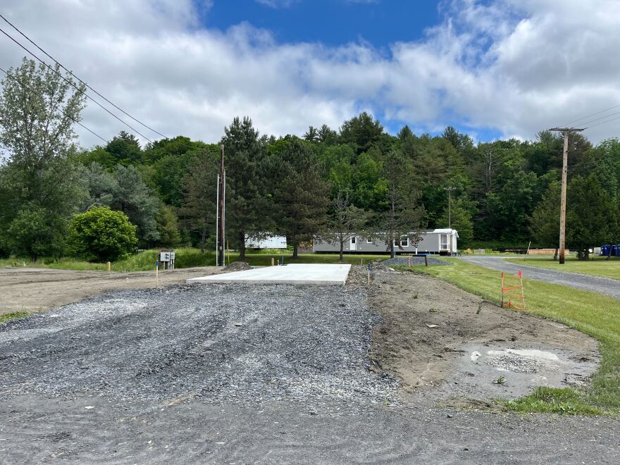 A gravel driveway leads to a spotless concrete pad
