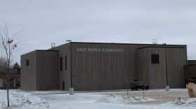 A large gray building on a snowy day. The side of the building says East Rapids Elementary in capital white letters.