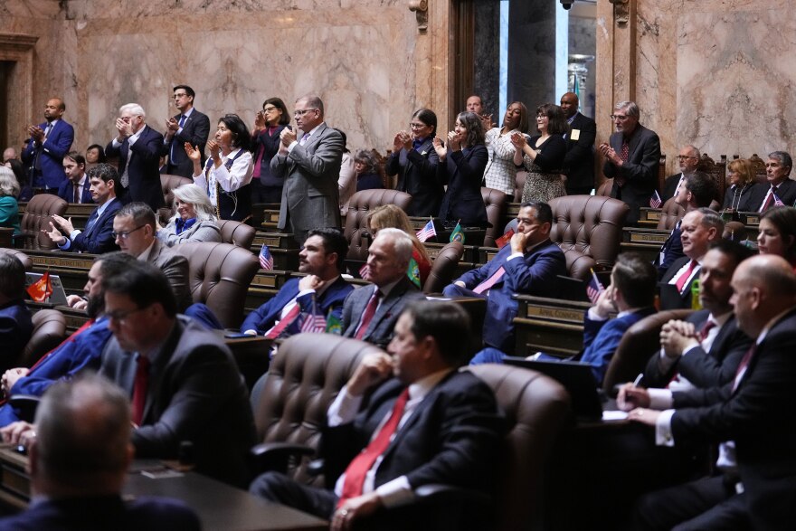 Some people stand and clap as others remain seated. 