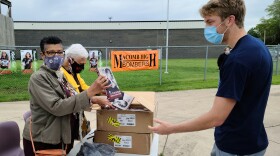 Denise Morse hands a copy of the book to MHS senior Adam Farr. Jo Anna Walker is standing next to Morse.