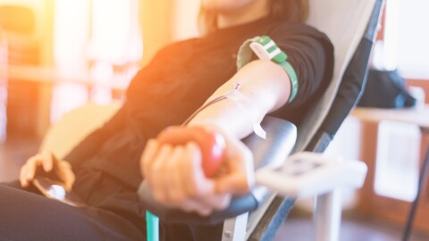 young woman as blood donor at donation with a bouncy ball holding in hand