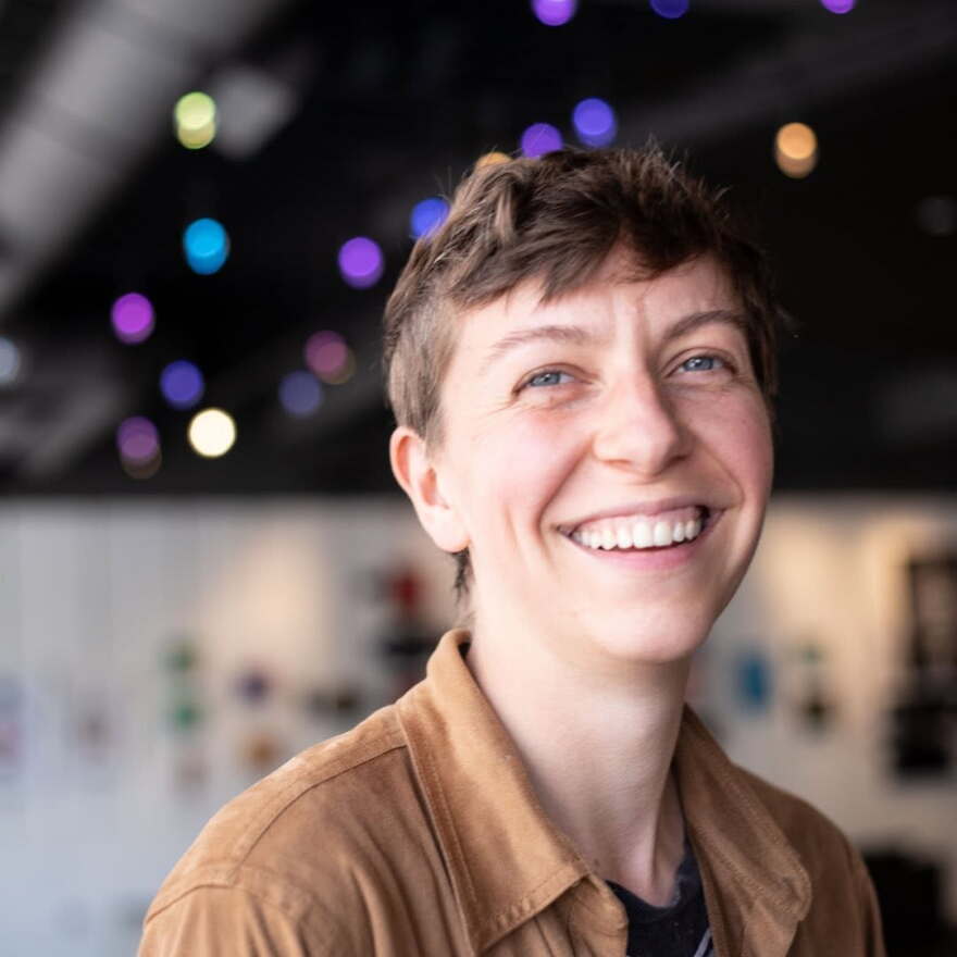 Person in a brown shirt smiling in an indoor space