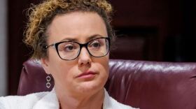 Woman with glasses looking forward during a meeting